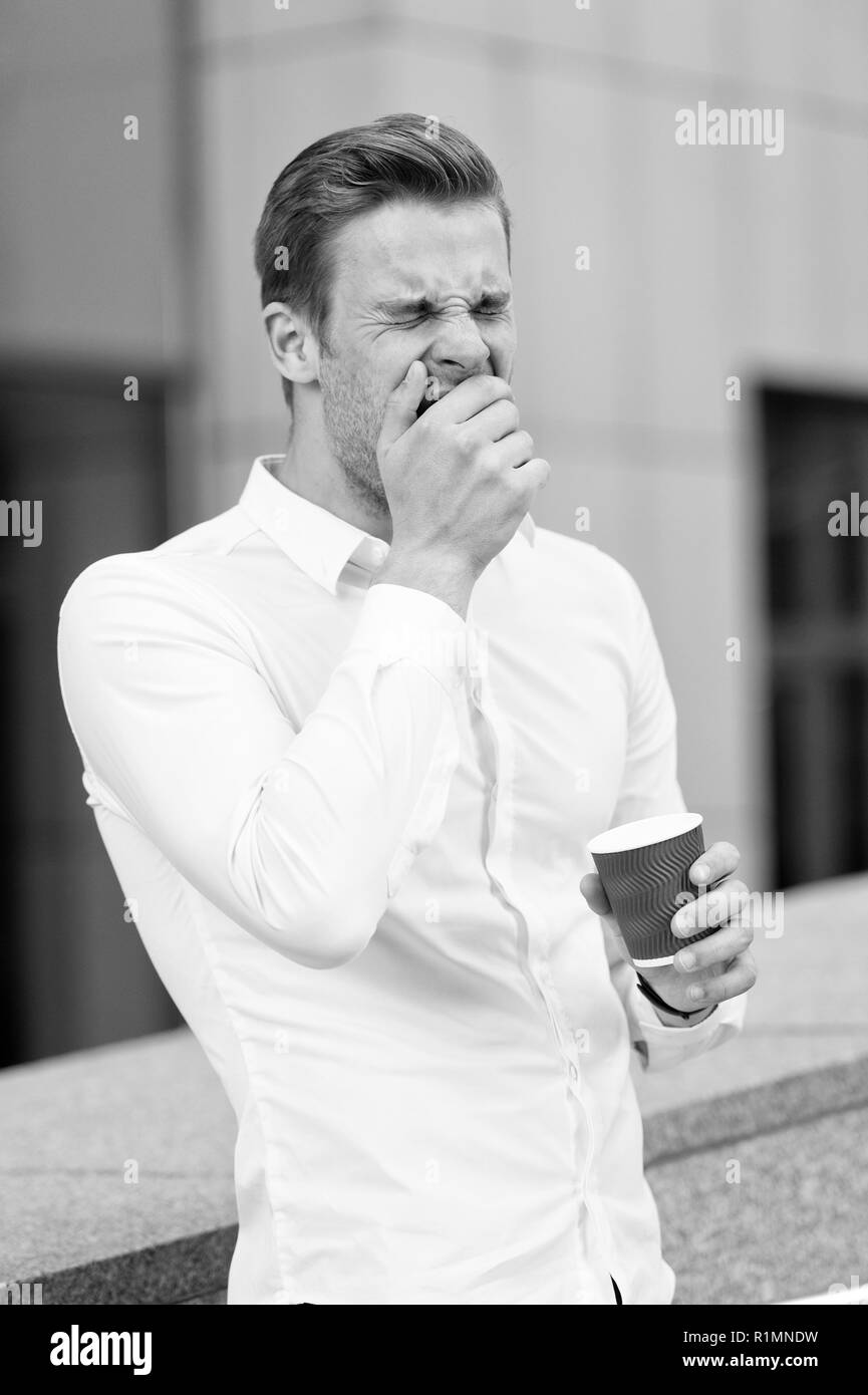 But first coffee. Man yawning drinks coffee urban background. Taking