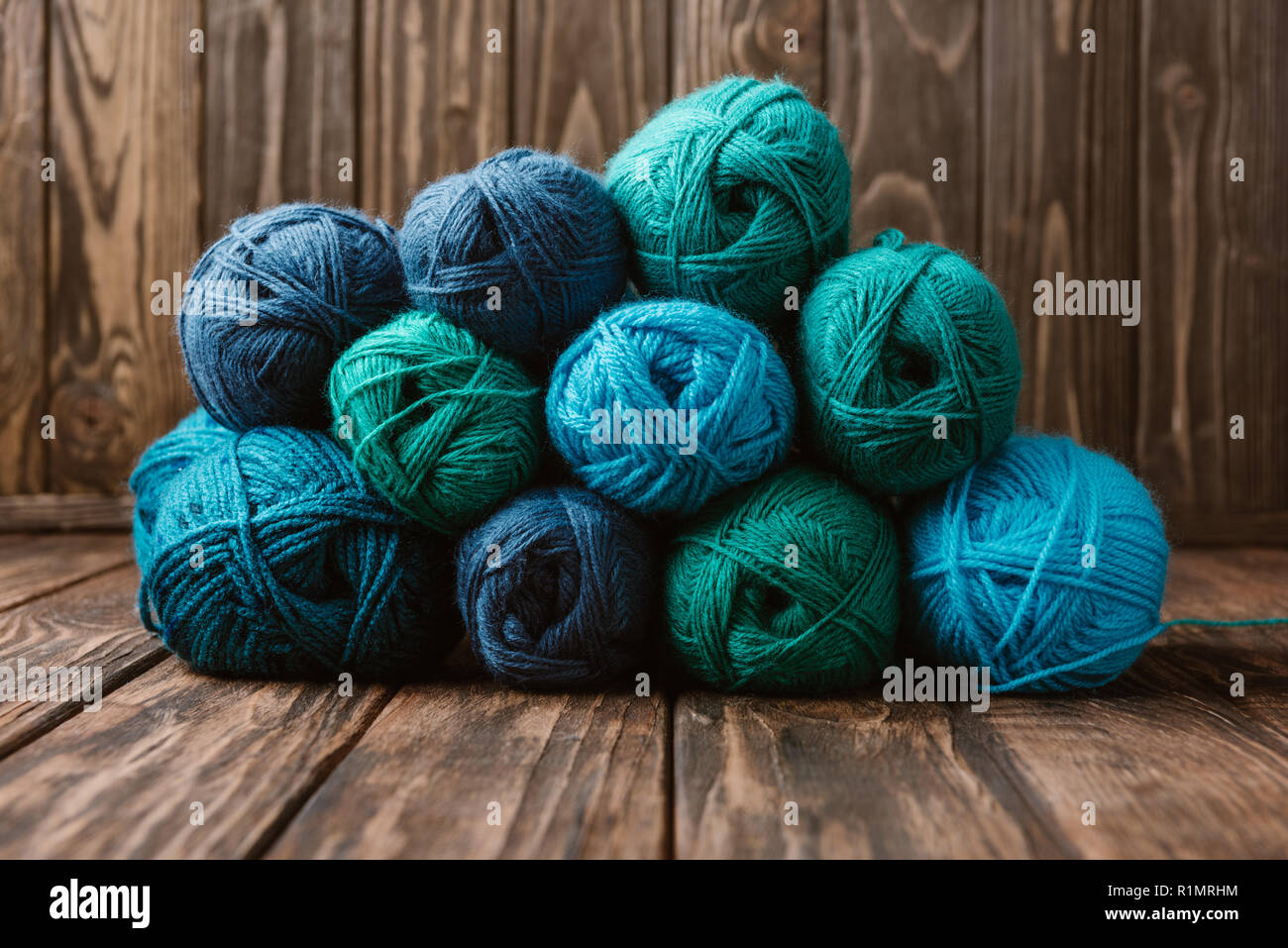 close up view of blue and green yarn clews on wooden surface Stock Photo