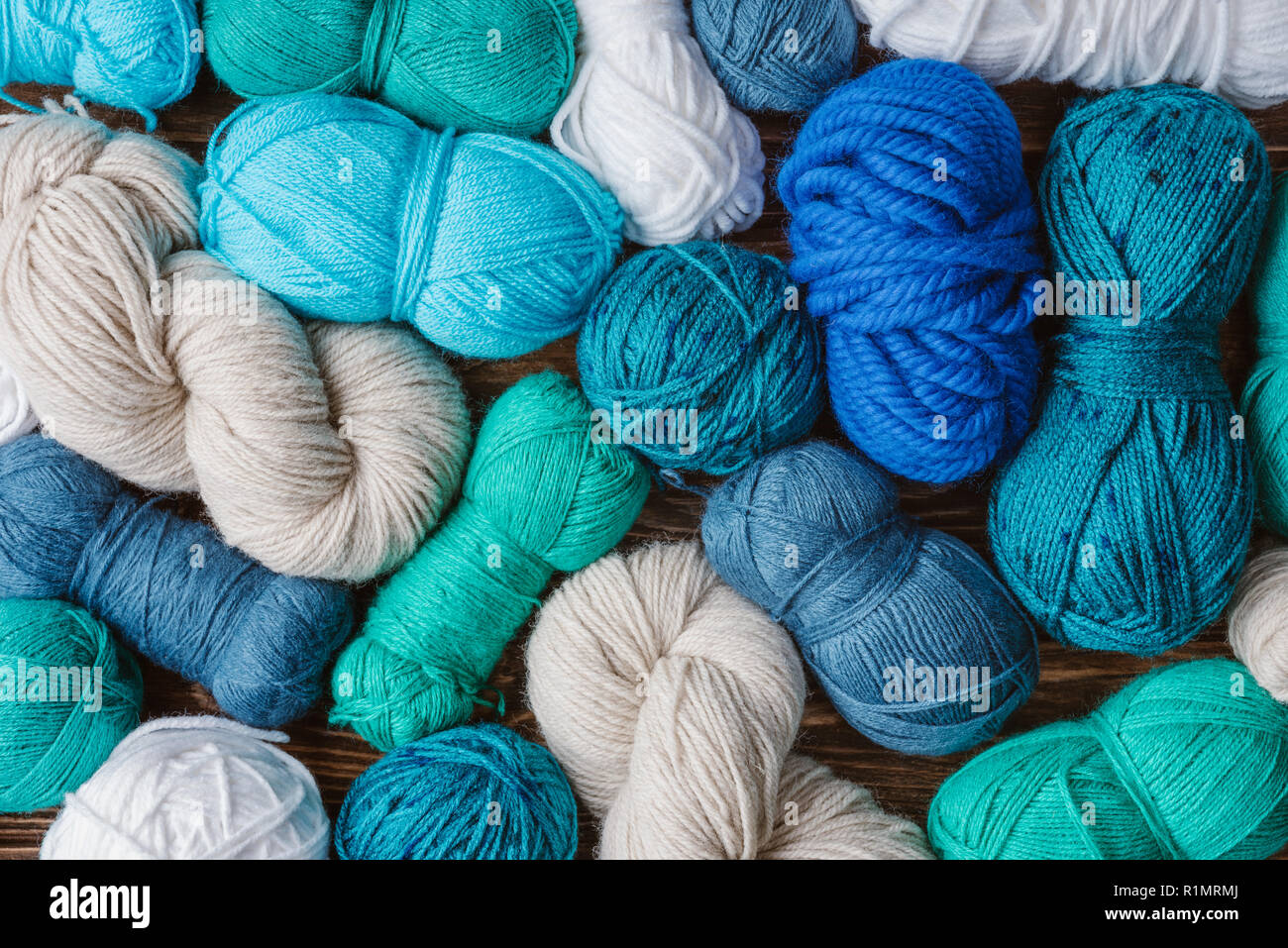 flat lay with arranged blue, white and green yarn clews on wooden
