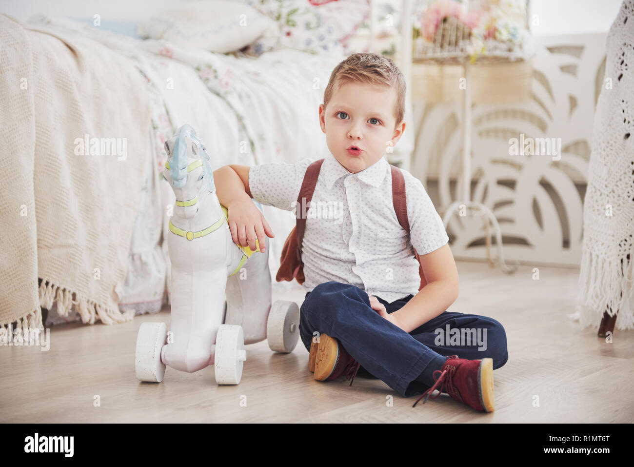 Cute little boy is going to school for the first time. Child with school bag and book. Kid makes a briefcase, child room on a background. Back to school Stock Photo