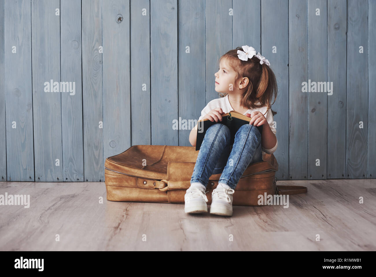 Ready to big travel. Happy little girl reading interesting book ...