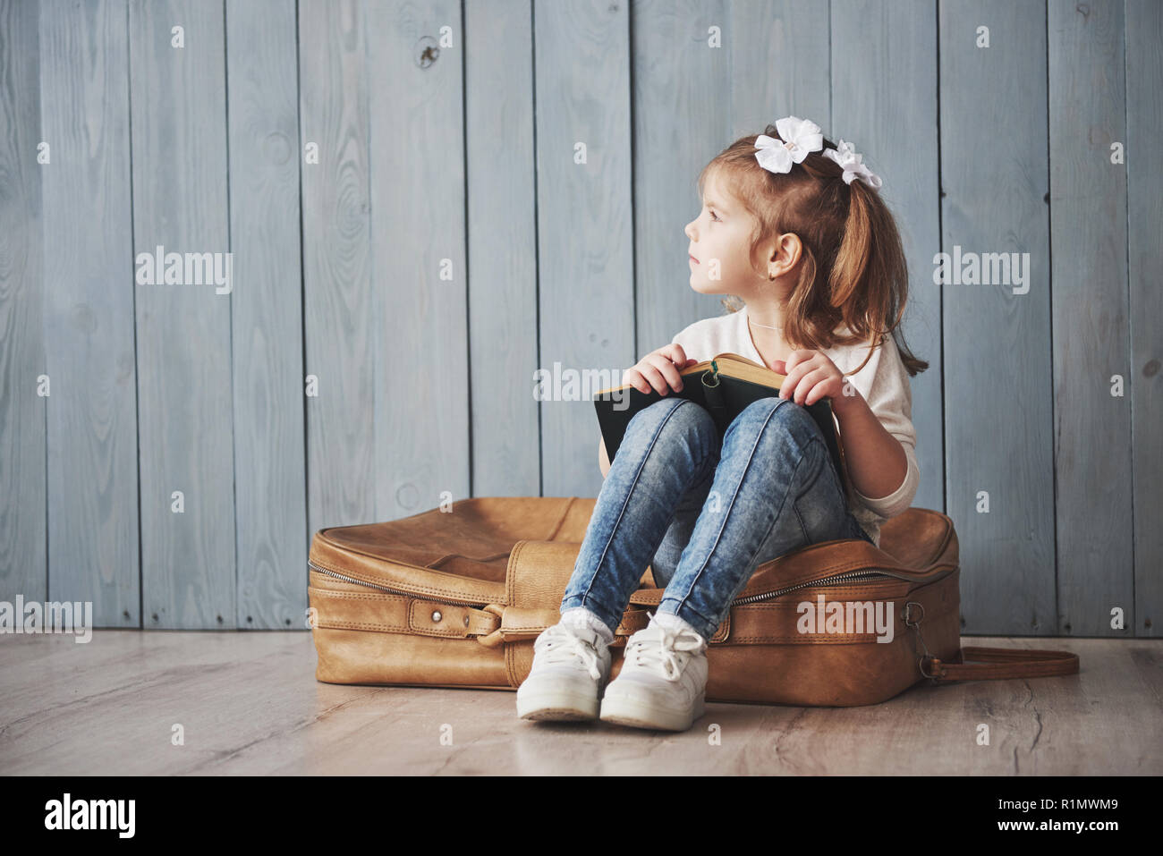 Ready to big travel. Happy little girl reading interesting book ...