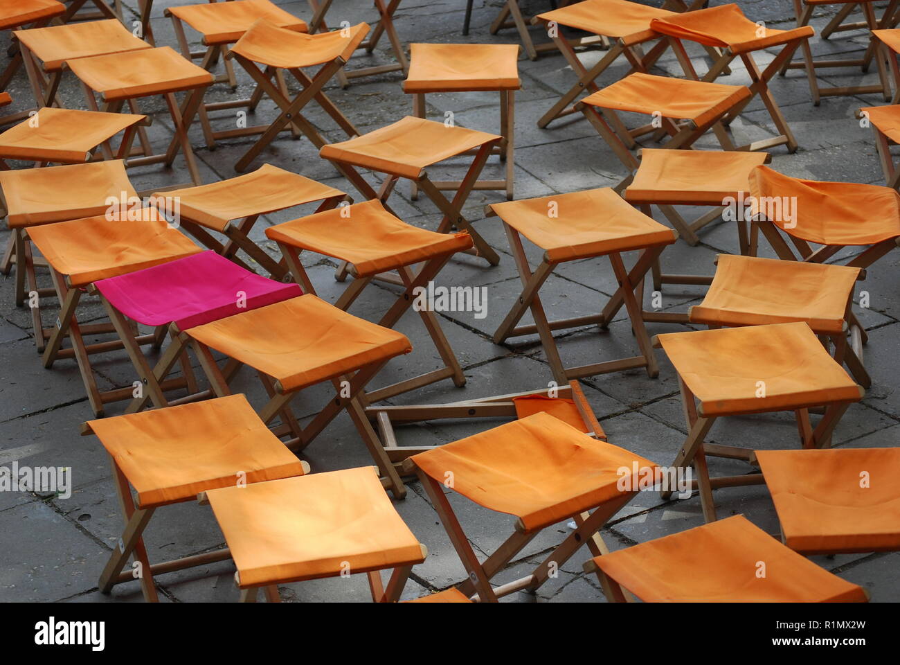 Pink chair surrounded by yellow ones Stock Photo