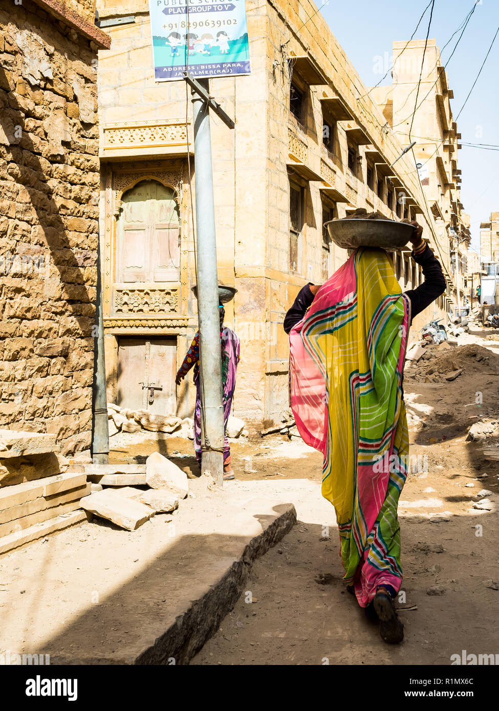 Women employed in construction works, carrying heavy bowls of rubble and soil on their heads. India Jaisalmer June 2018 Stock Photo