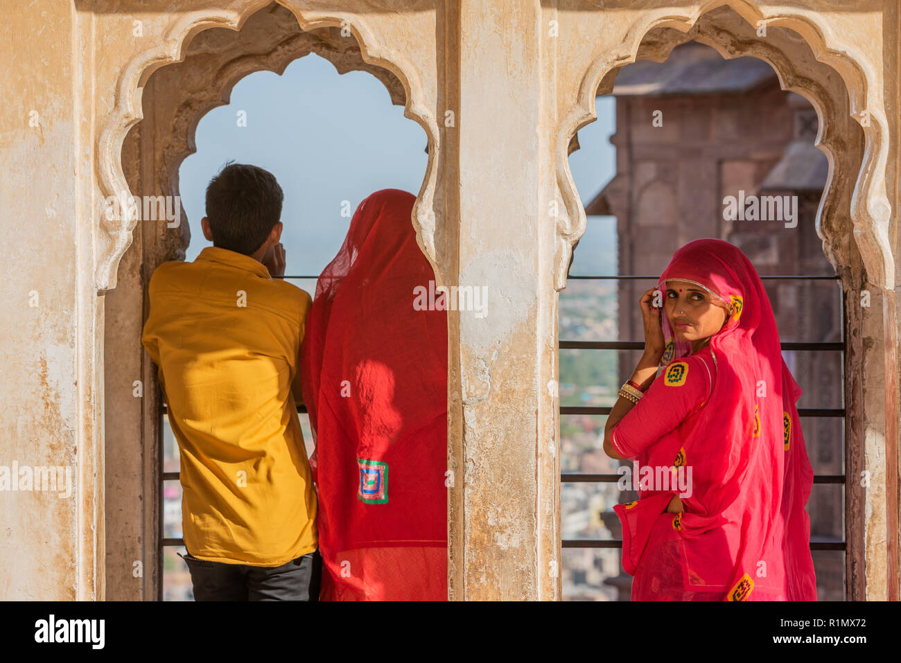 Three Rajasthani people dressed in colourful clothes enjoy the view from Jodhpur palace, India. Stock Photo