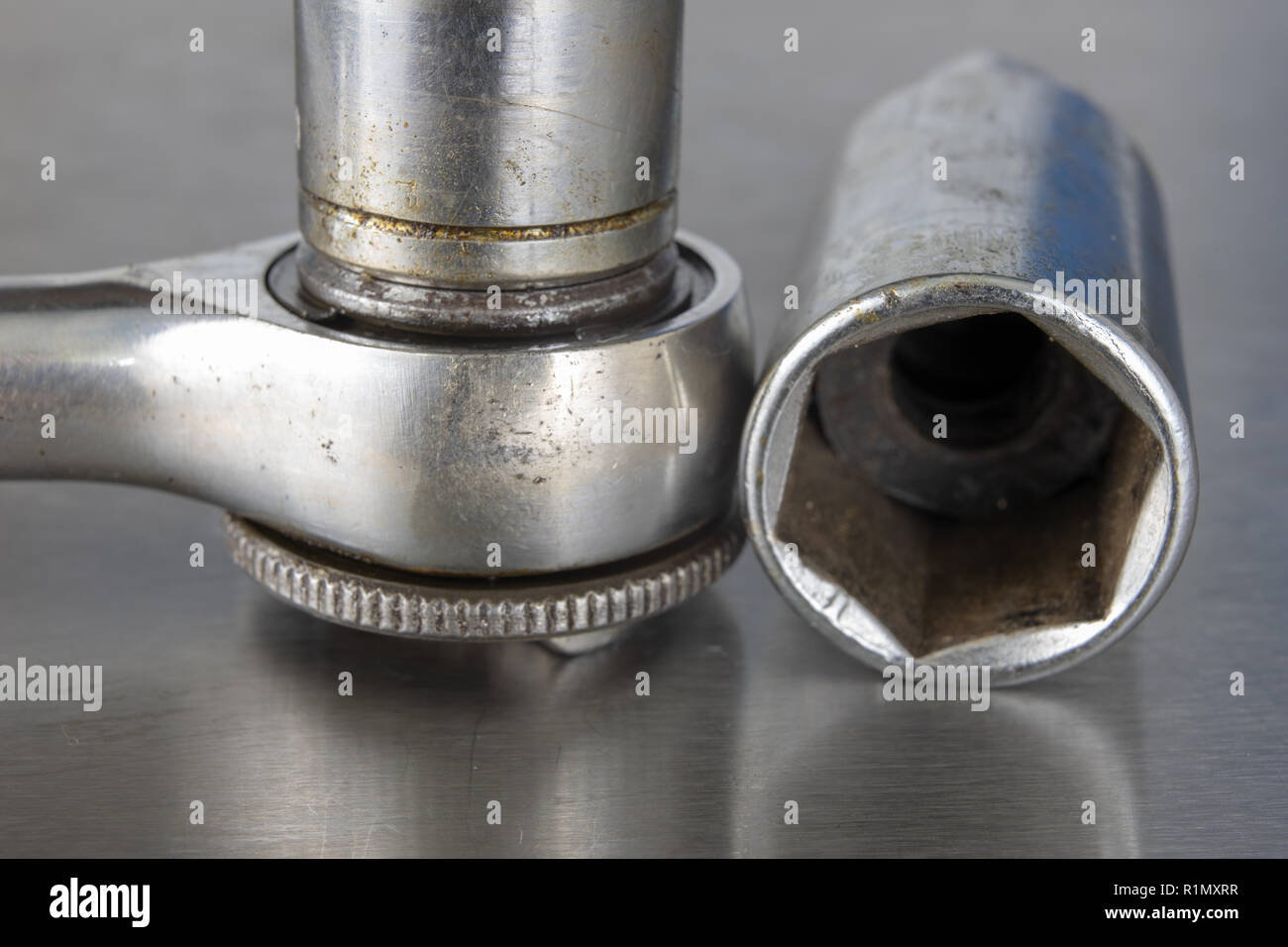 Old socket wrenches with a handle. Accessories for a workshop mechanic on a tin table. Light background. Stock Photo