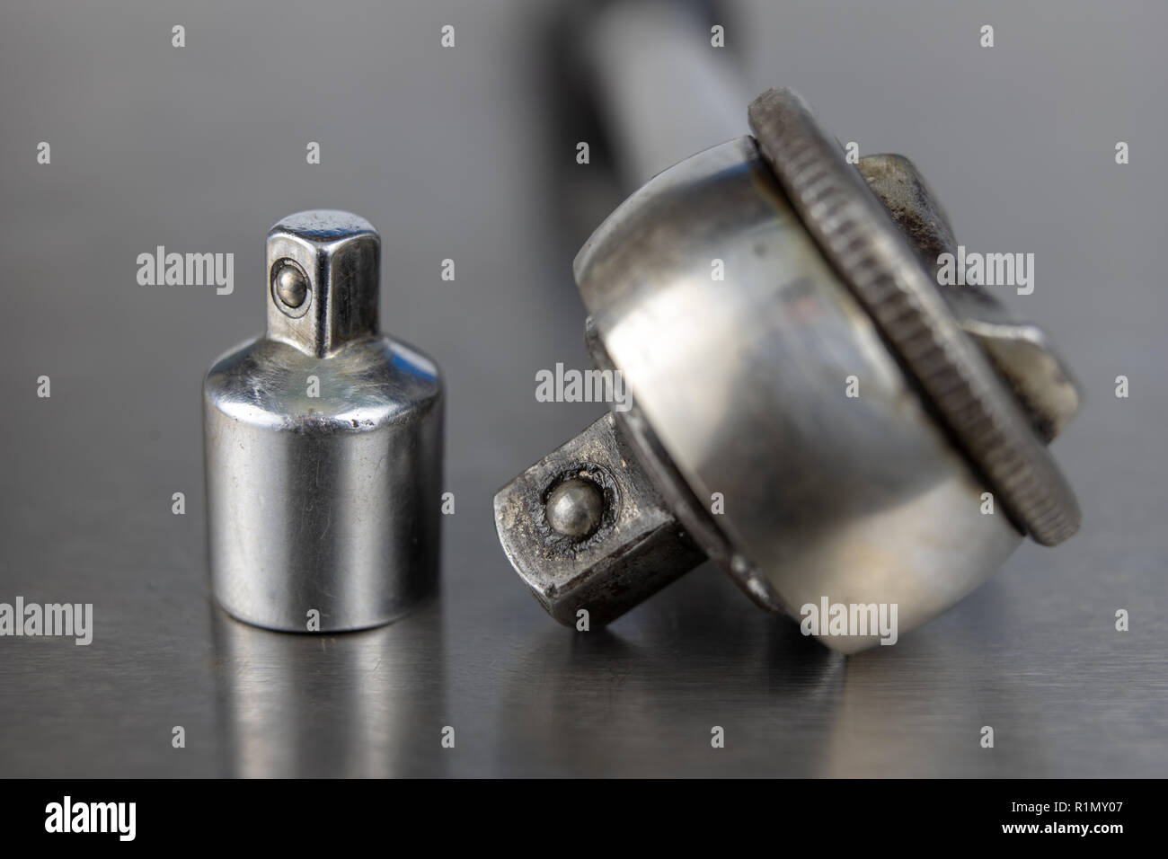 Old socket wrenches with a handle. Accessories for a workshop mechanic on a tin table. Light background. Stock Photo