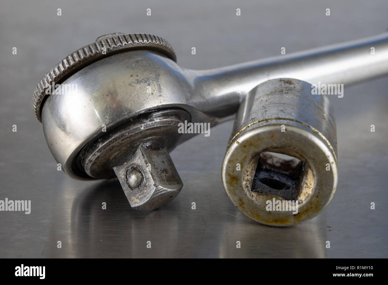 Old socket wrenches with a handle. Accessories for a workshop mechanic on a tin table. Light background. Stock Photo
