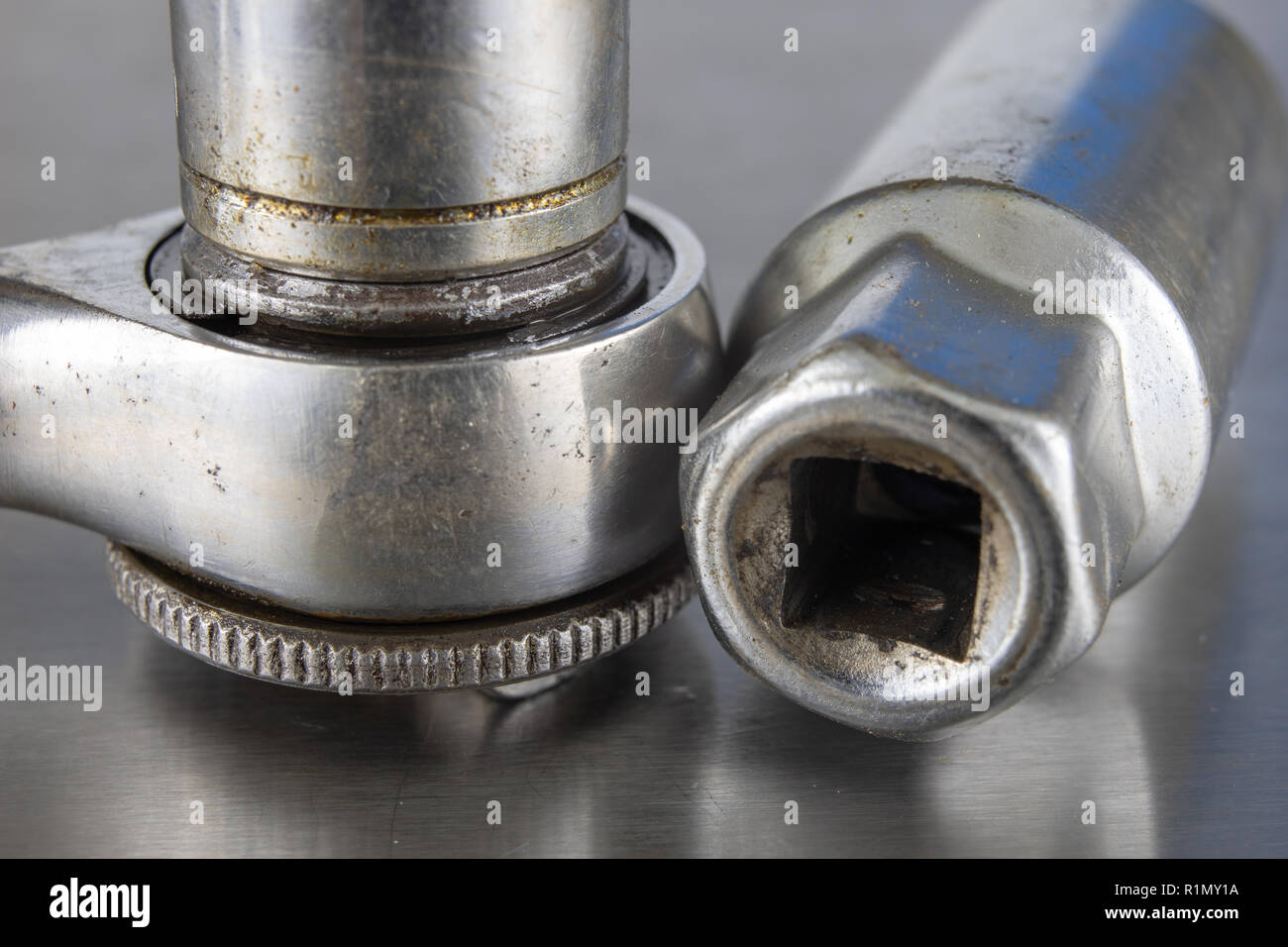 Old socket wrenches with a handle. Accessories for a workshop mechanic on a tin table. Light background. Stock Photo