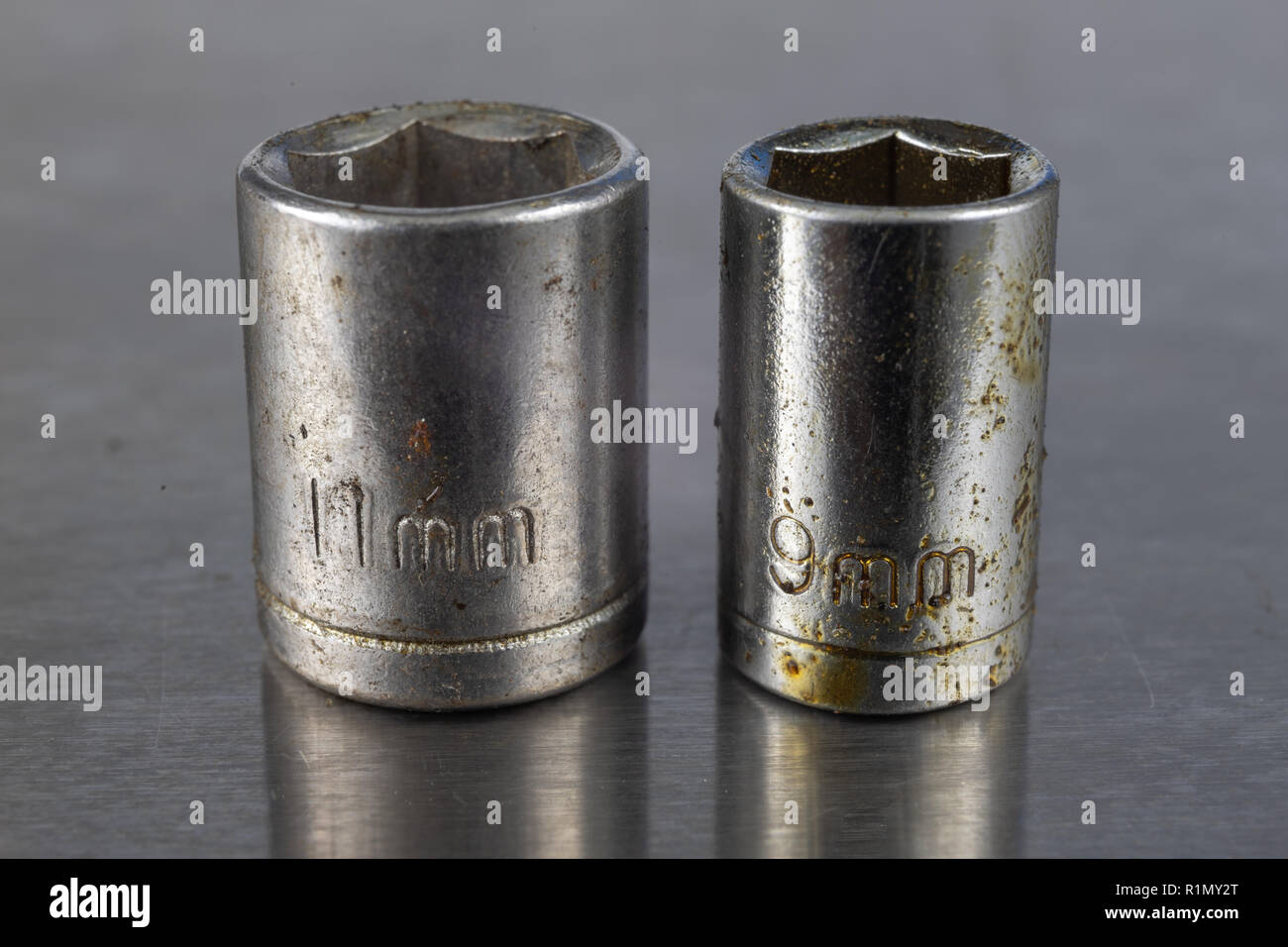 Old socket wrenches with a handle. Accessories for a workshop mechanic on a tin table. Light background. Stock Photo