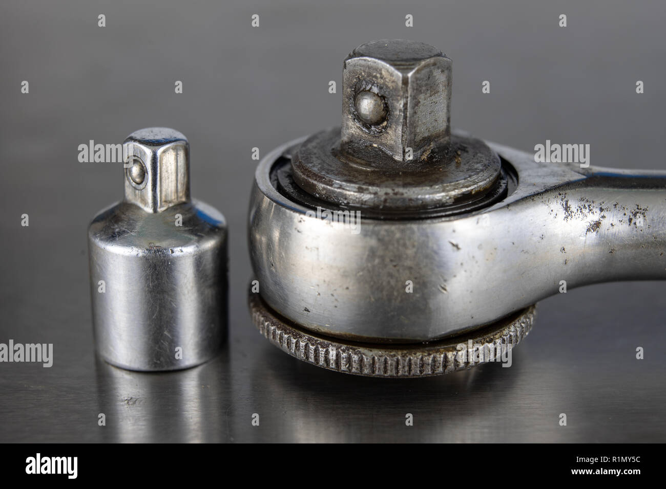 Old socket wrenches with a handle. Accessories for a workshop mechanic on a tin table. Light background. Stock Photo