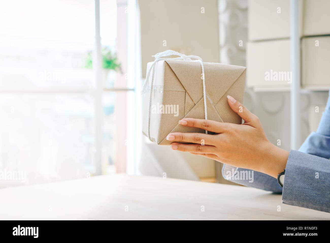 Close up hands holding gift box wrapped with kraft paper Stock Photo