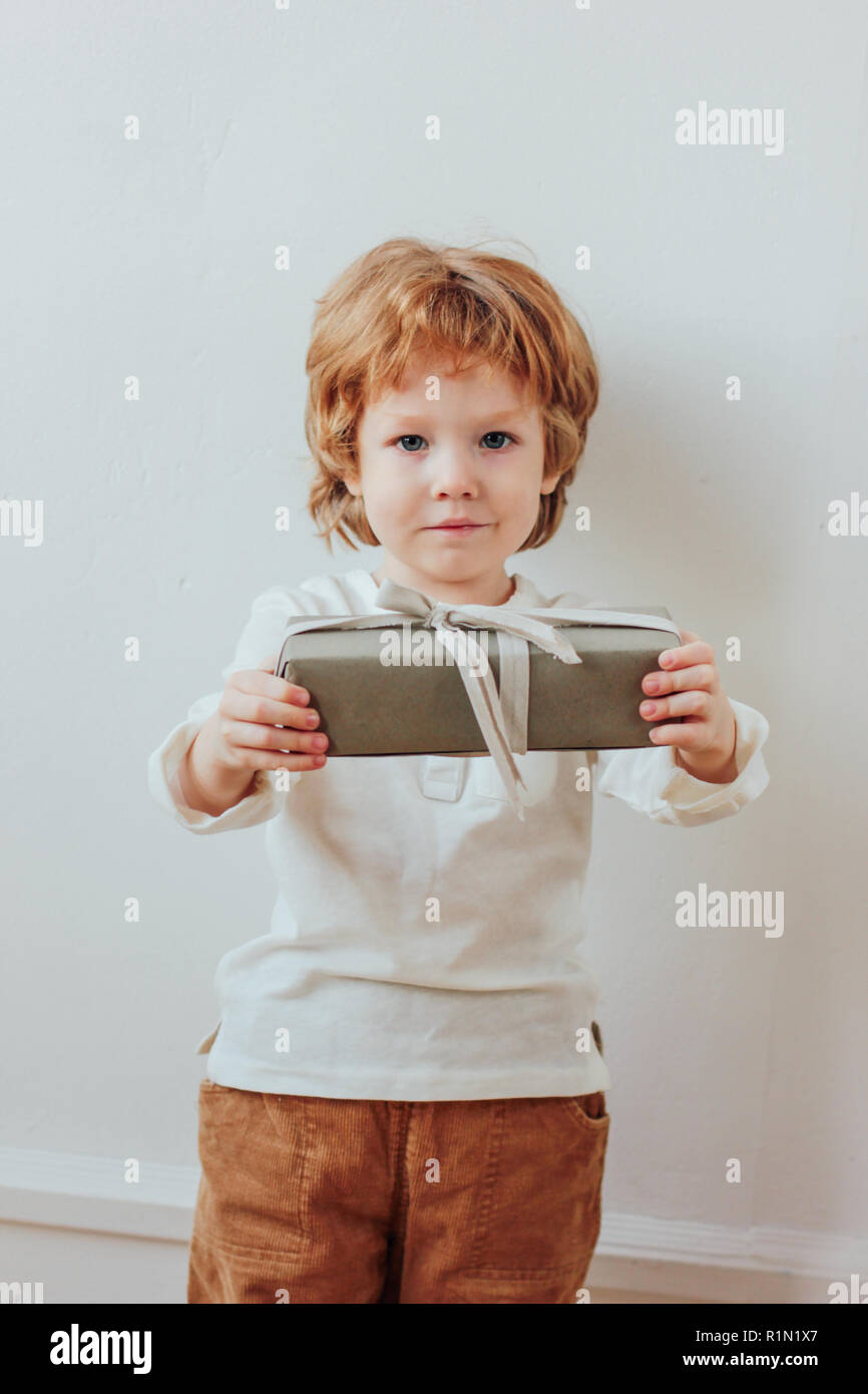 Pretty little boy holding gift box, minimalism style Stock Photo Alamy