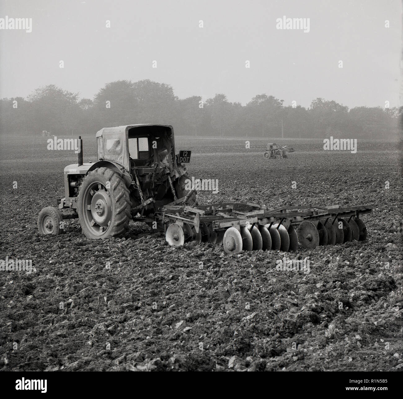 Farming, 1950s, a tractor in a field with plouging equipment attached. Stock Photo