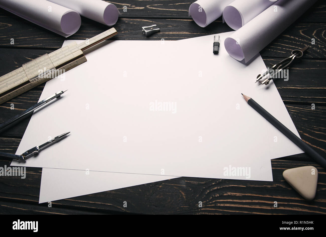 On a wooden table are drawings, compasses, pencil, elastic, ruler and sharpener. Stock Photo