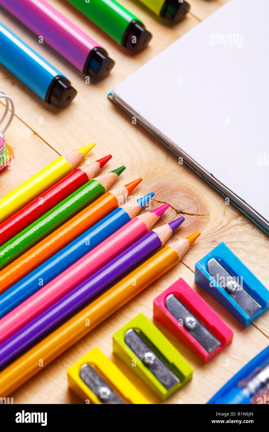 Bright crayons, markers and sharpeners along with a notebook on the table Stock Photo