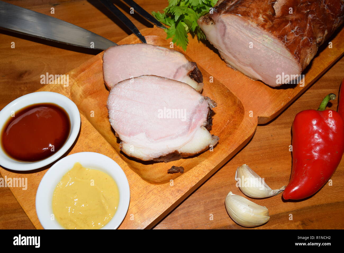 Kassler on wooden rustic plate. It is often served with sauerkraut and mashed potatoes. Fully Cooked cured and smoked pork loin chops on a wooden tray. Stock Photo