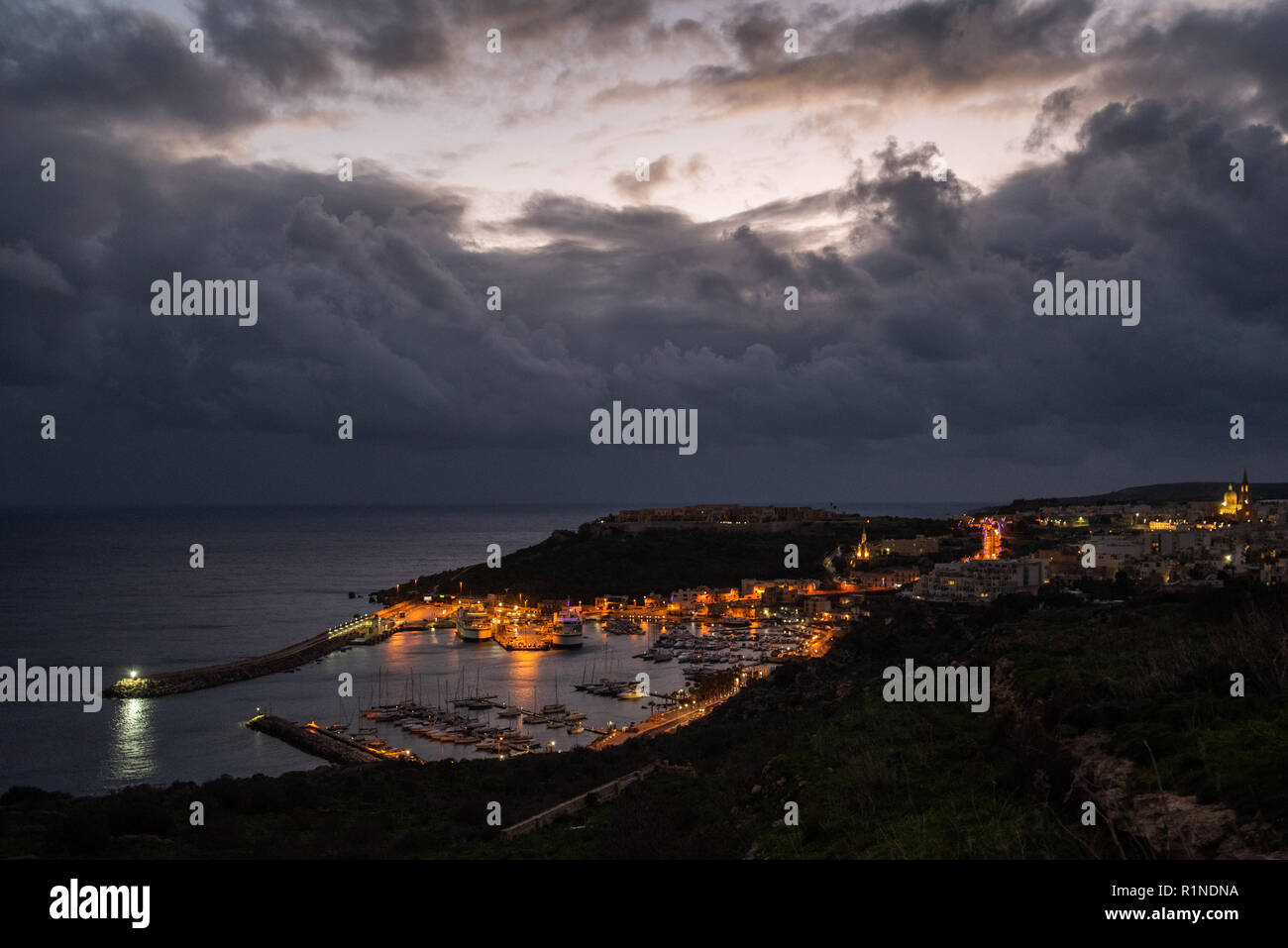Lights shining in the distance in the harbour in Gozo, Malta on a stormy evening. Stock Photo