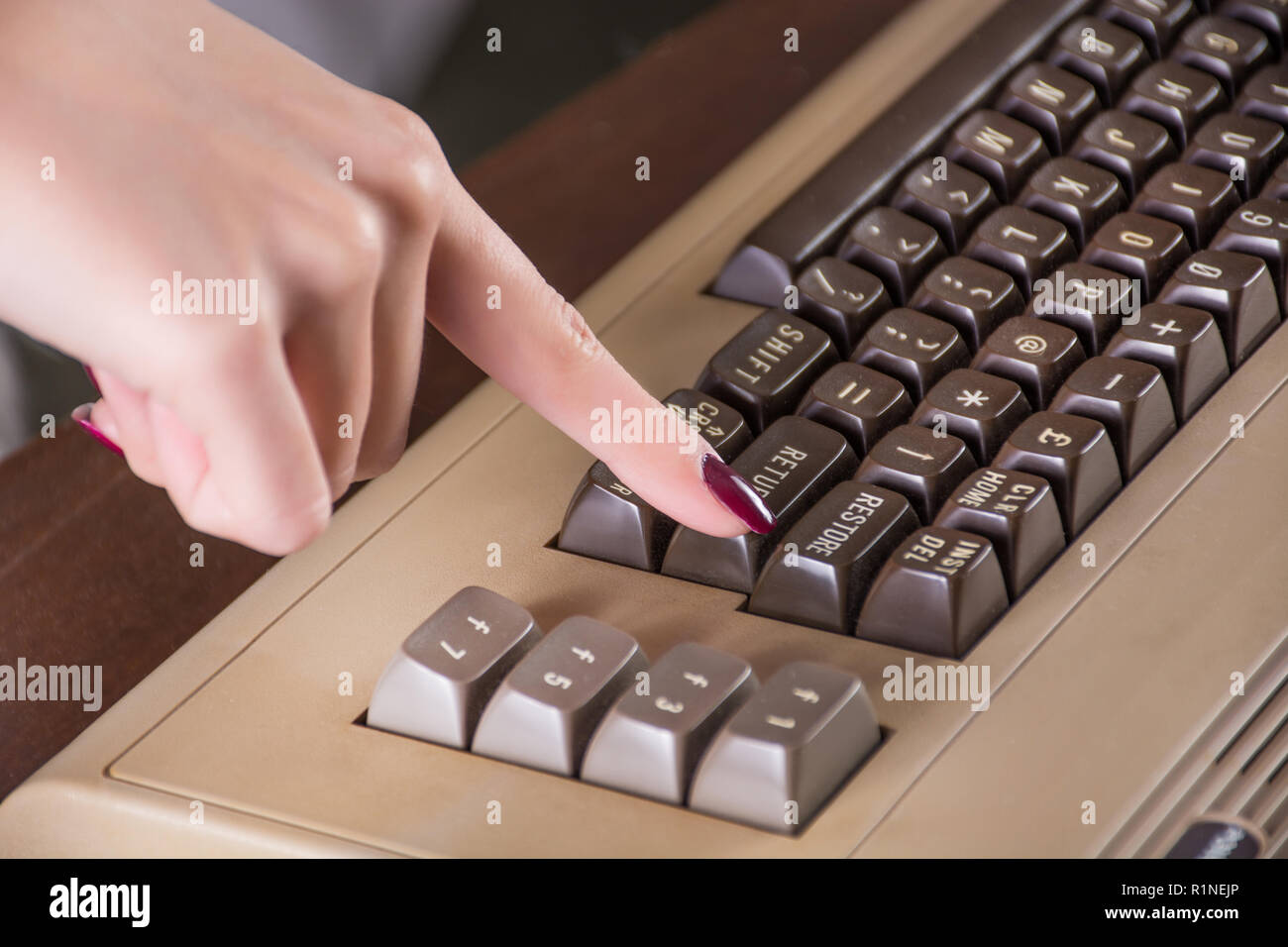 Girl finger push button on old computer keyboard on office desk. Retro
