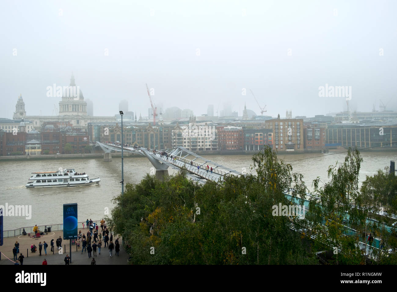 London, UK - 30th October 2016: Looking across the River Thames and the London Millennium Footbridge towards St Pauls Cathedral and The City of London on a foggy autumn day Stock Photo