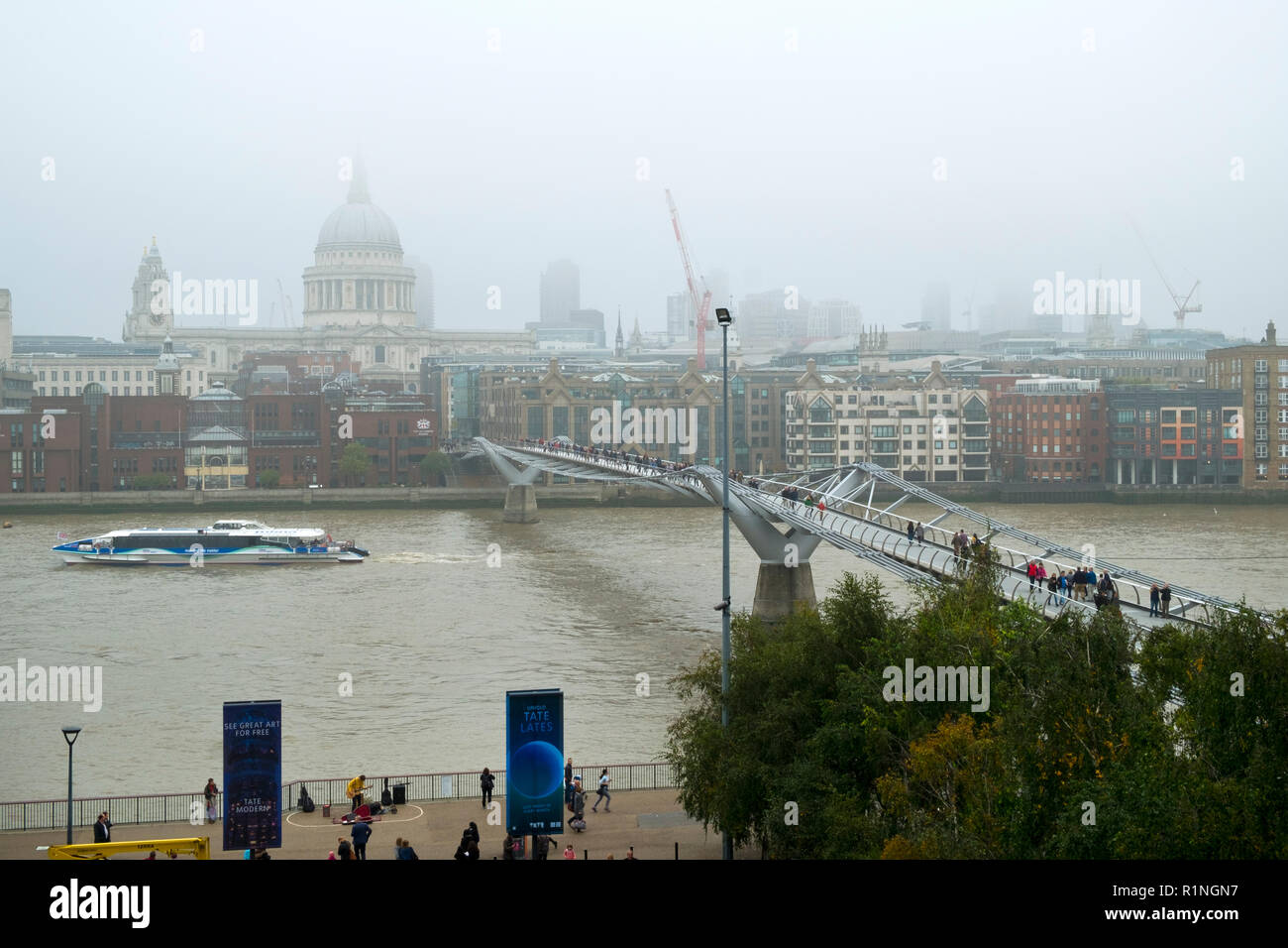 London, UK - 30th October 2016: Looking across the River Thames and the London Millennium Footbridge towards St Pauls Cathedral and The City of London on a foggy autumn day Stock Photo
