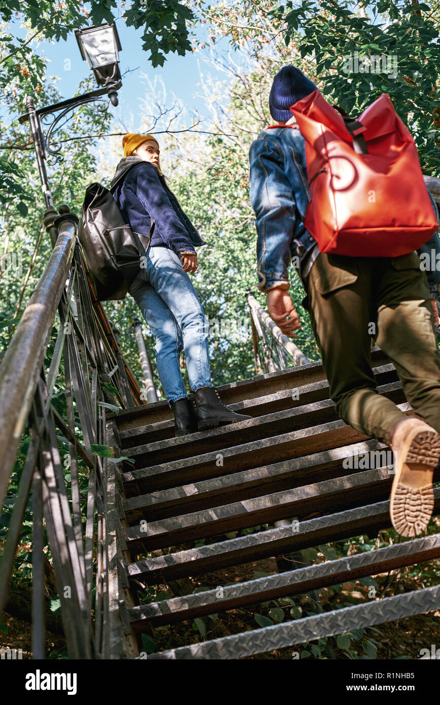 Happy romantic couple of tourists are ascending on steps. Rear view Stock Photo