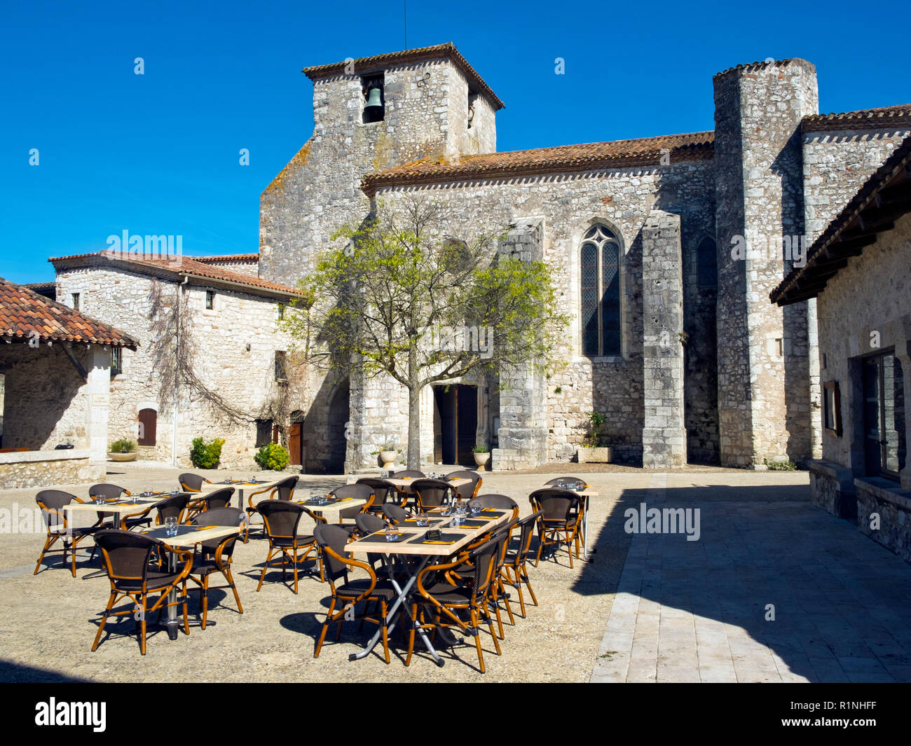 Restaurant tables prepared for lunchtime in the square in Pujols, Lot-et-Garonne, France. This historic fortified village stronghold is now a member of 'Les Plus Beaux Villages de France' association. Stock Photo