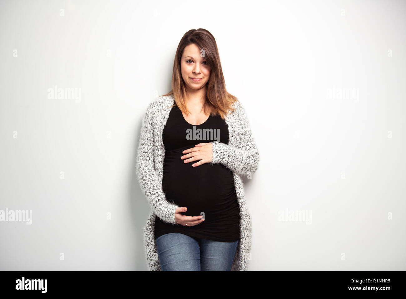 A Portrait of happy pregnant woman with hands on stomach isolated over white background Stock Photo