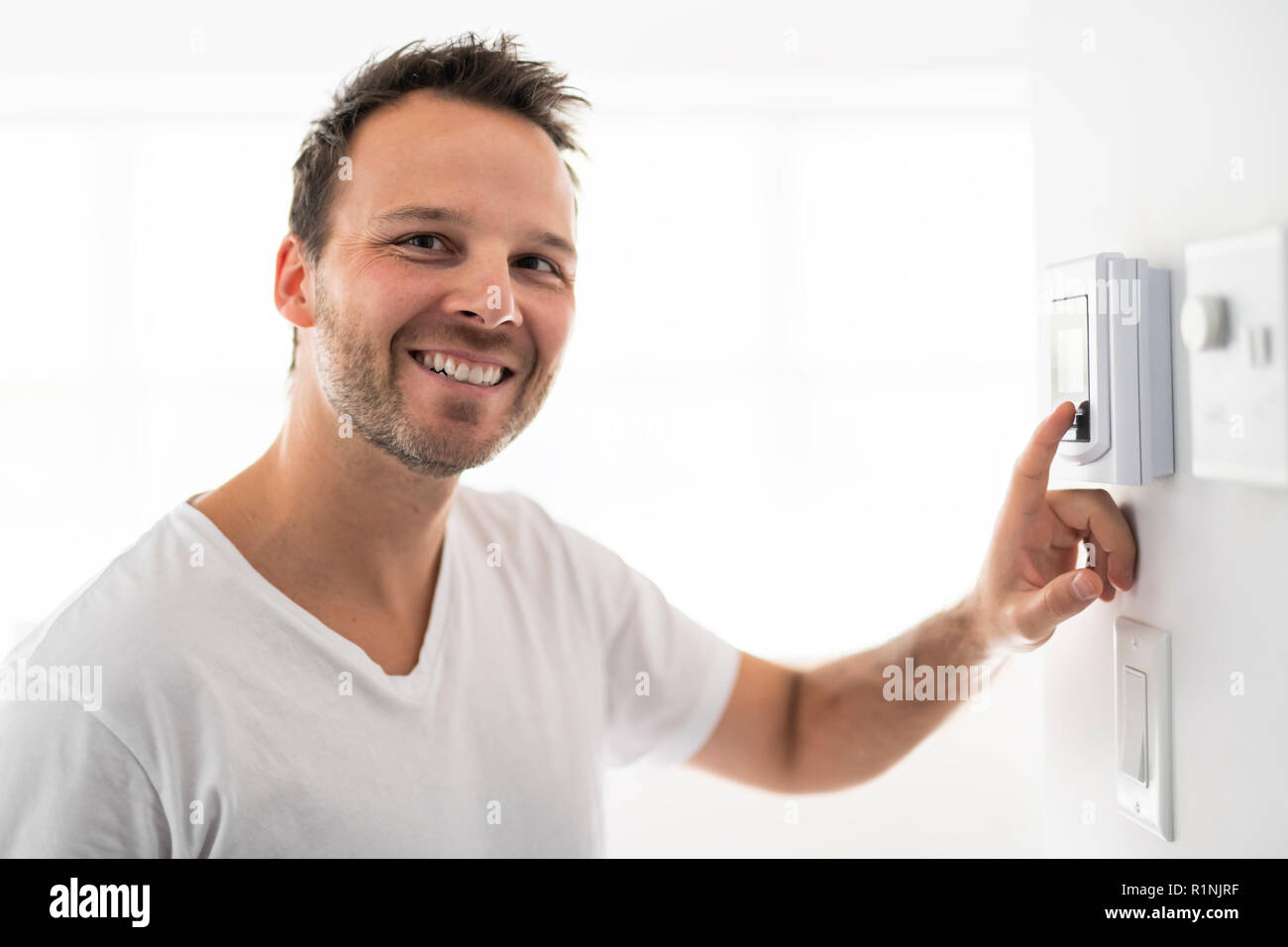 A man set the thermostat at house Stock Photo Alamy