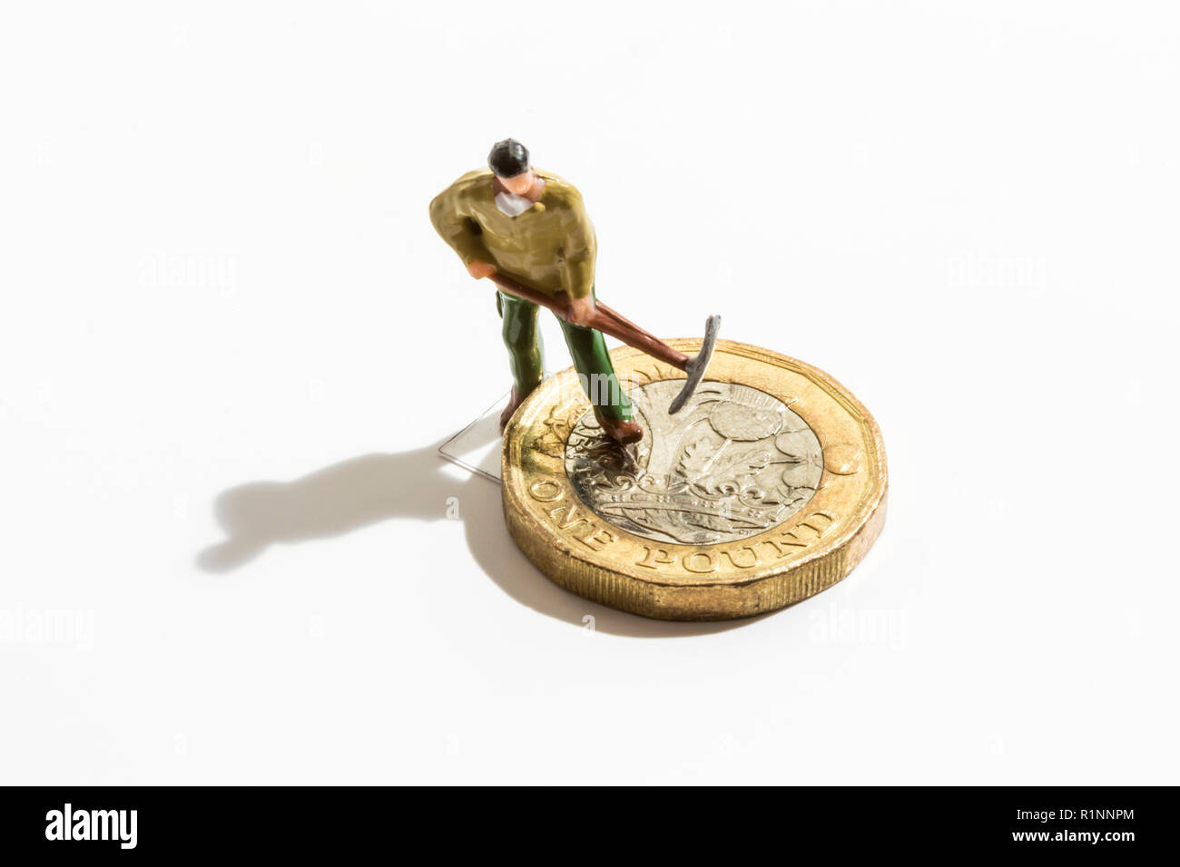 Making or destroying money. Pound coin with miniature workman. Stock Photo