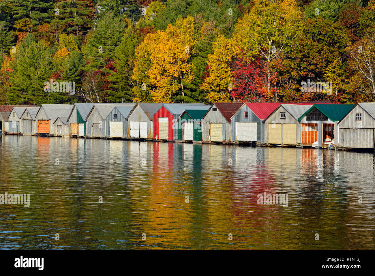 Boat houses reflected in the waters of Penage/Panache Lake at the