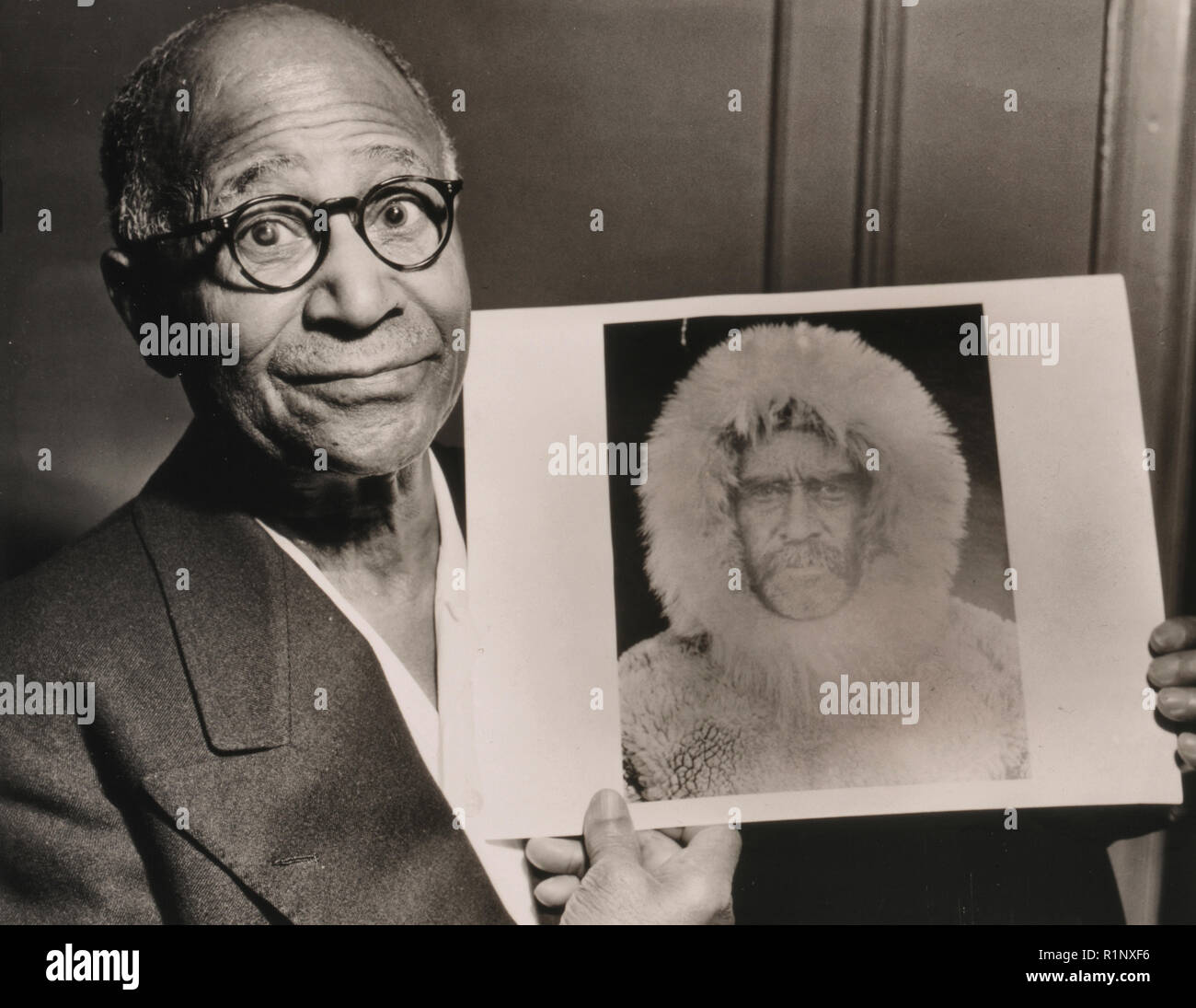 Matthew Henson, head-and-shoulders portrait, facing front, holding a portrait of Robert E. Peary taken during an expedition to the North Pole, 1953 Stock Photo