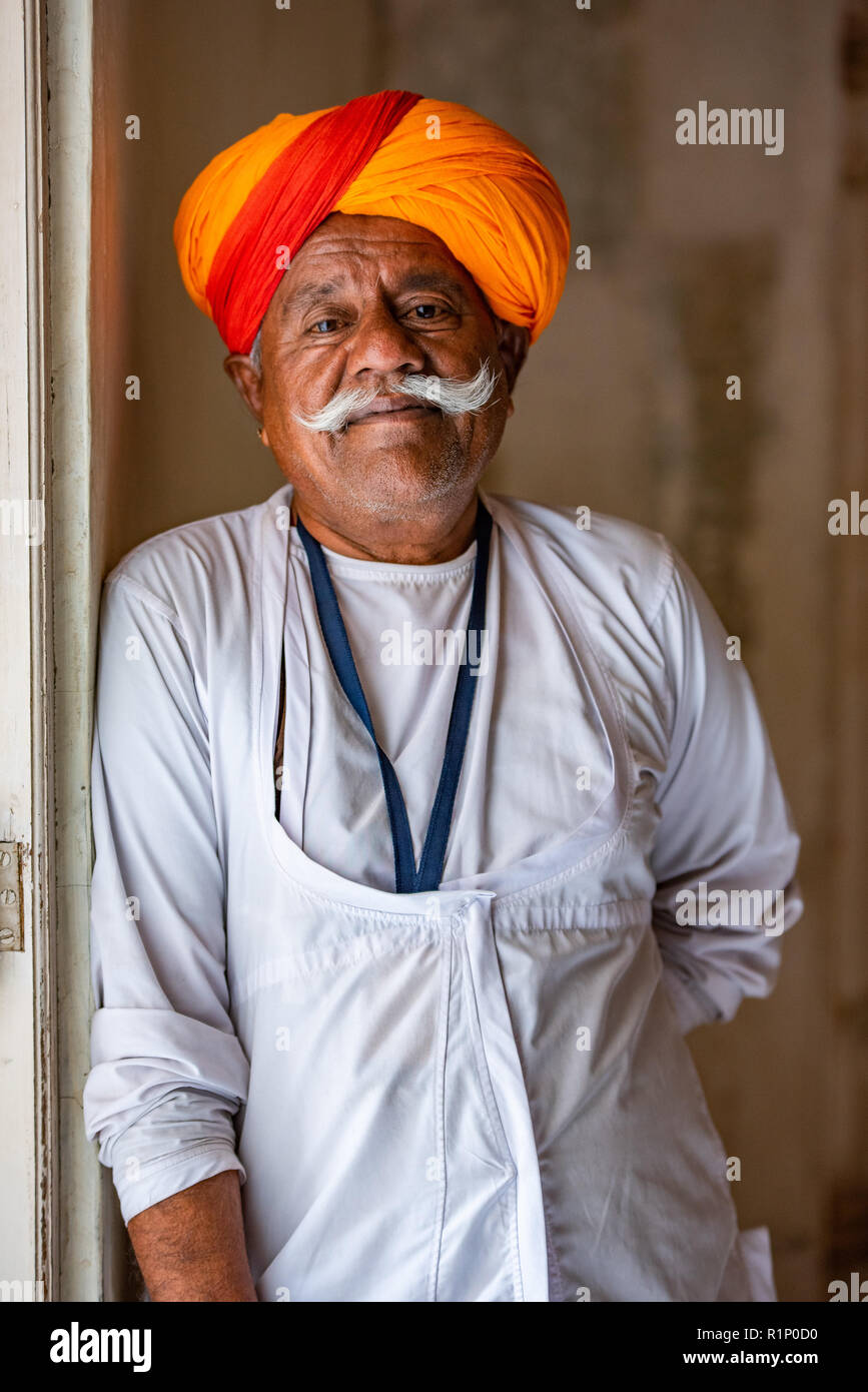 Portrait of a Rajasthani gentleman with impressive moustache dressed in a traditional Kurta with saffron turban in Jodhpur palace, India Stock Photo