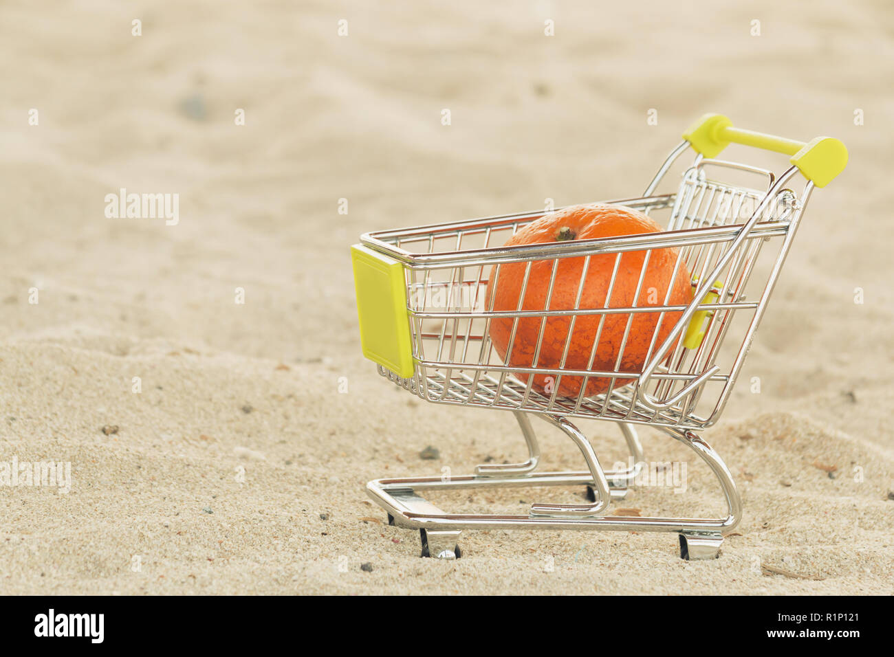 Shopping cart with tangerine mandarin fruit standing on the sand. New year fruit. Healthy diet food Stock Photo