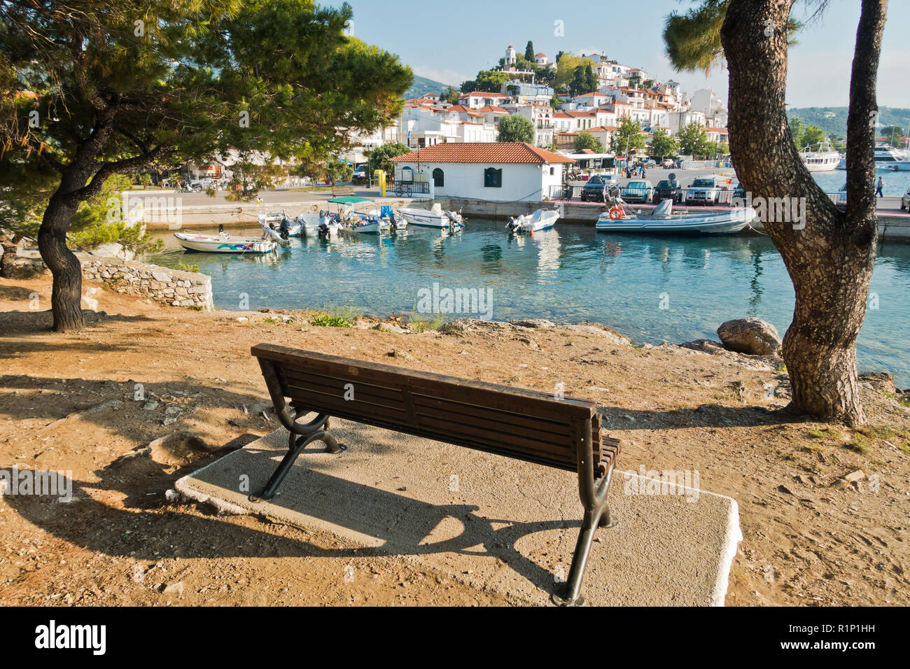 Bench at small island with a view of Skiathos town waterfront and harbor, Skiathos island, Greece Stock Photo