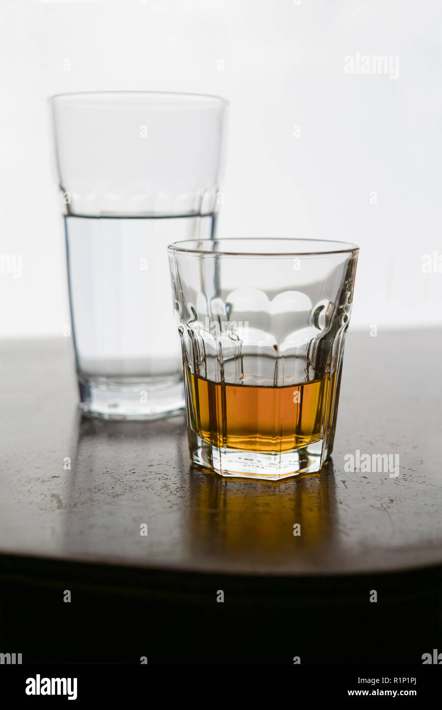 In front, a glass of alcohol, behind, a glass of water. Stock Photo