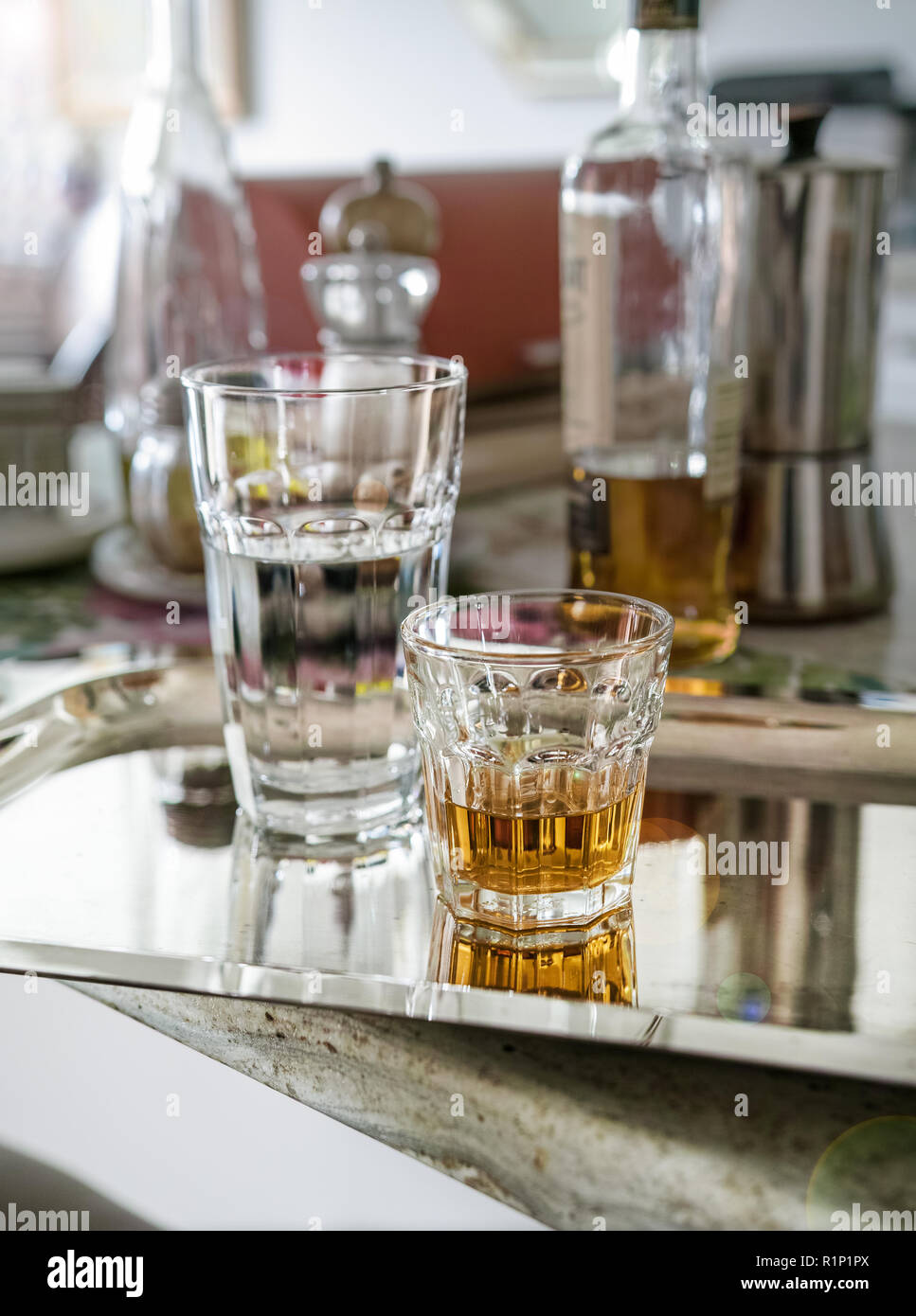 After the party, on the kitchen counter, a glass of alcohol and a large glass of water remain on the silver tray. Stock Photo