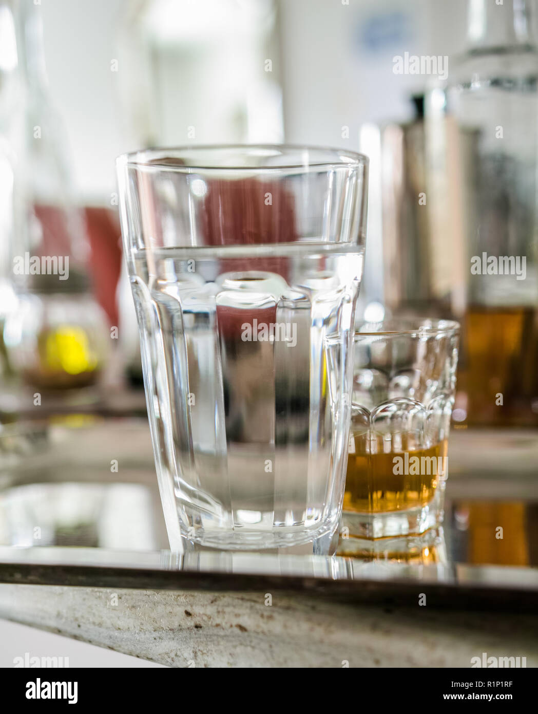After the party, on the kitchen counter, a glass of alcohol and a large glass of water remain on the tray. Stock Photo