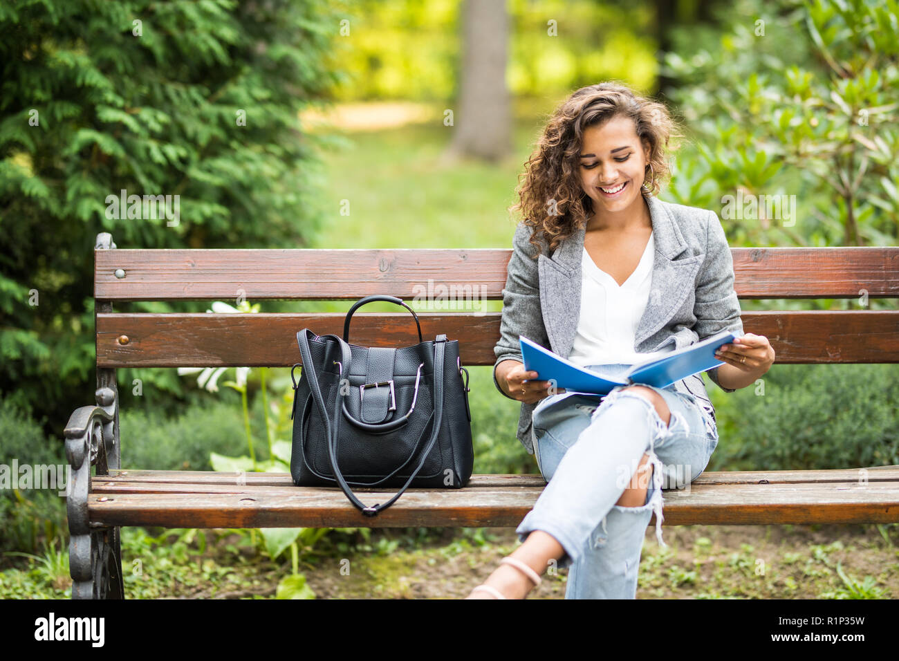 The girl sitting on a bench, reading a book Stock Photo - Alamy