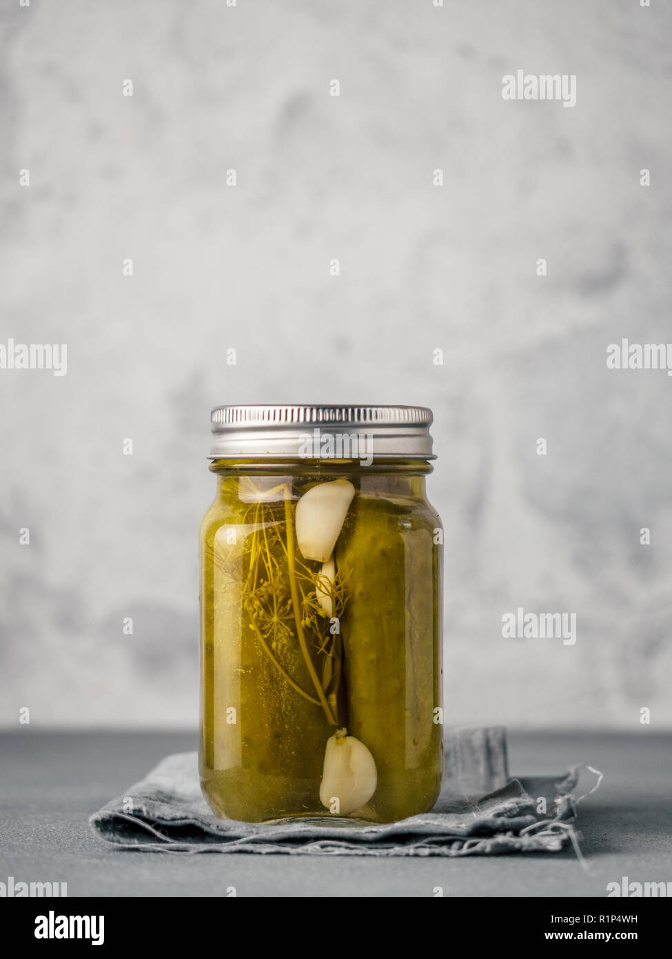 Glass jar with pickled cucumbers on gray background with copy space for text. Perfect homemade