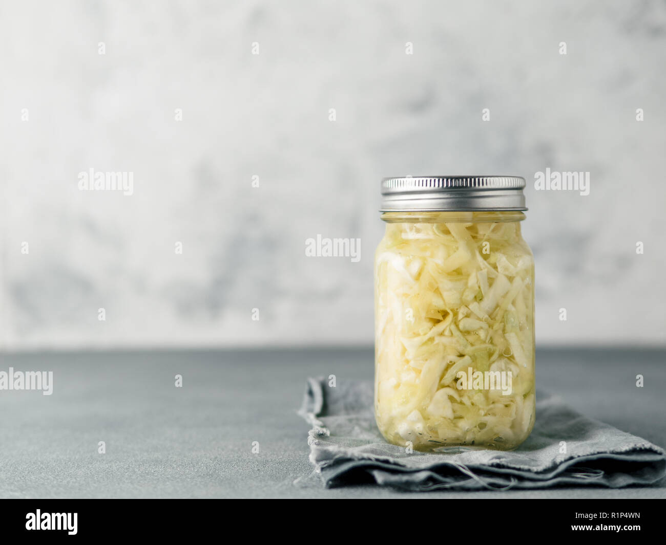 Sauerkraut in glass mason jar. Pickling cabbage at home on table. The