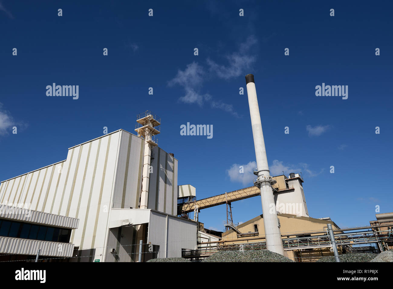 Glass factory buildings with a chimney on a sunny blue sky day. Stock Photo