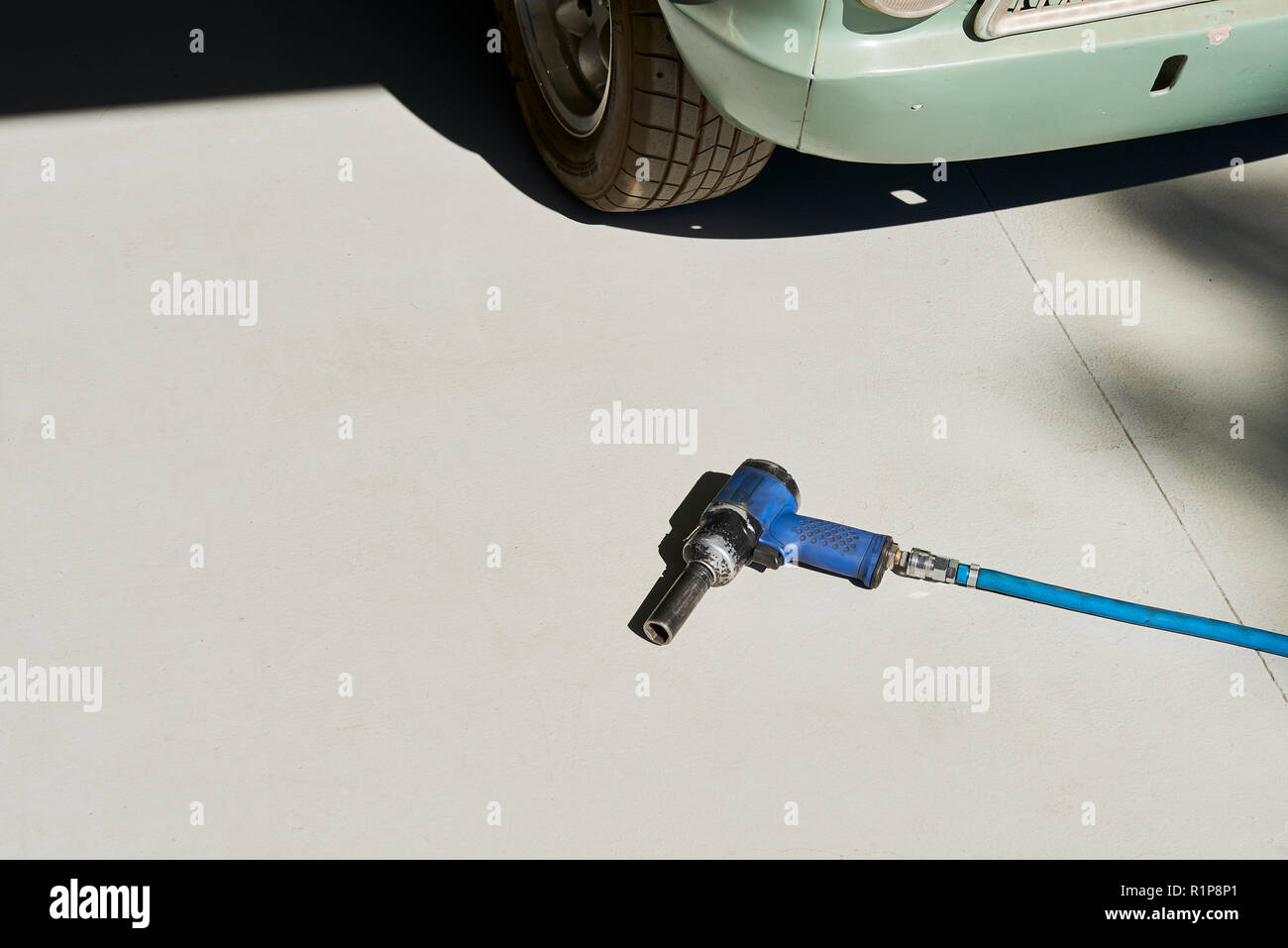 Blue impact wrench rattle gun laying in front of a car on a