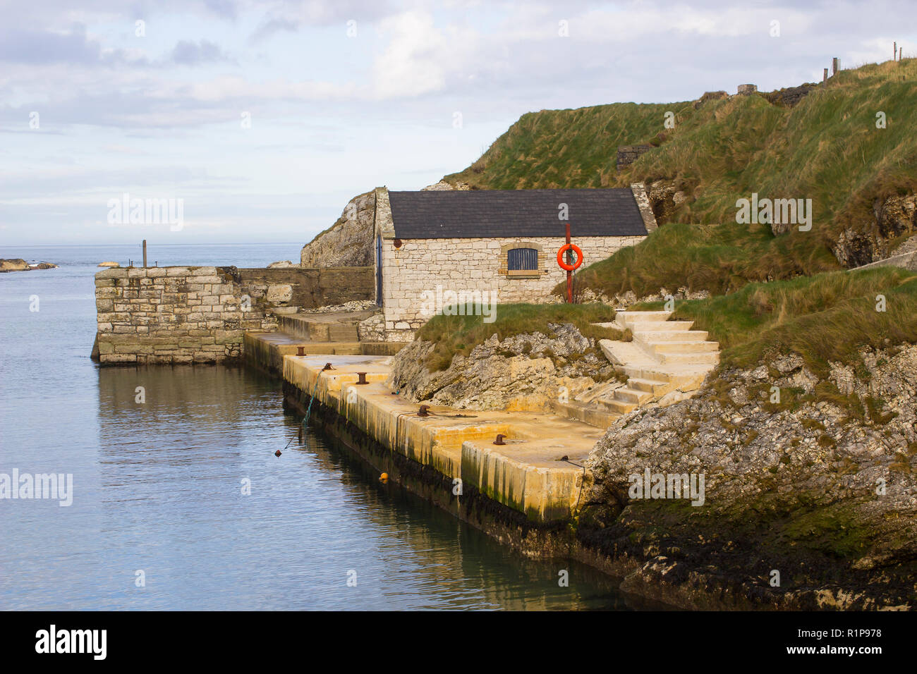 The small harbor at Ballintoy on the North Antrim Coast of Northern Ireland with its ancient stone built boathouse on a day in spring Stock Photo