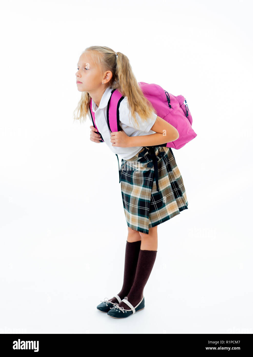 Sweet little girl in uniform carrying heavy big pink backpack or school