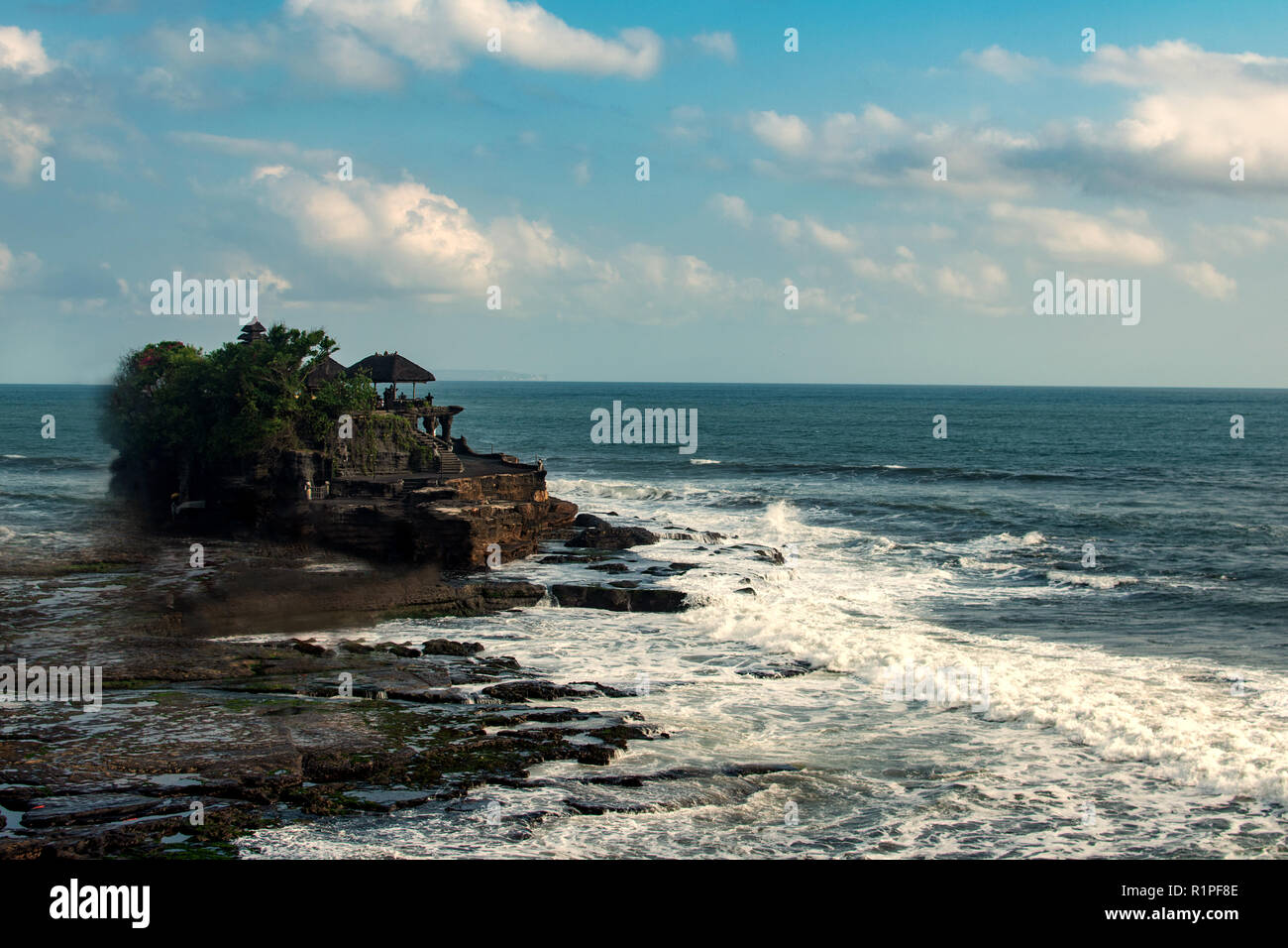 Chimeric temple on the water. Water temple in Bali. Indonesia nature landscape. Famous Bali landmark. Splashing waves and stone. Cloudy day in Indonesia. Water and rocks before storm Stock Photo