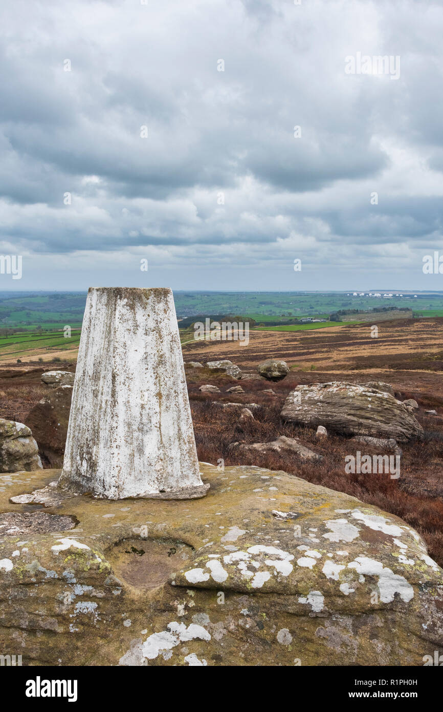 Close-up of Heyshaw Moor trig point perched high on moorland outcrop with scenic rural views to Menwith Hill - near Harrogate, North Yorkshire, GB, UK Stock Photo