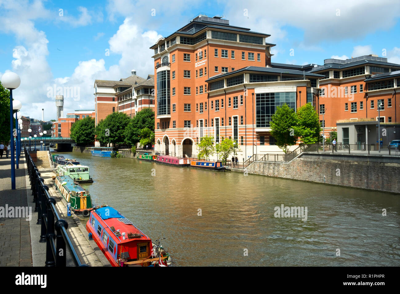 Bristol, UK - 4th August 2016: Moored canal boats and modern office blocks along The Floating Harbour and Temple Back (Temple Quay) regeneration business area in central Bristol City, UK. Workers leave their workplaces during a sunny summertime lunch break. Stock Photo