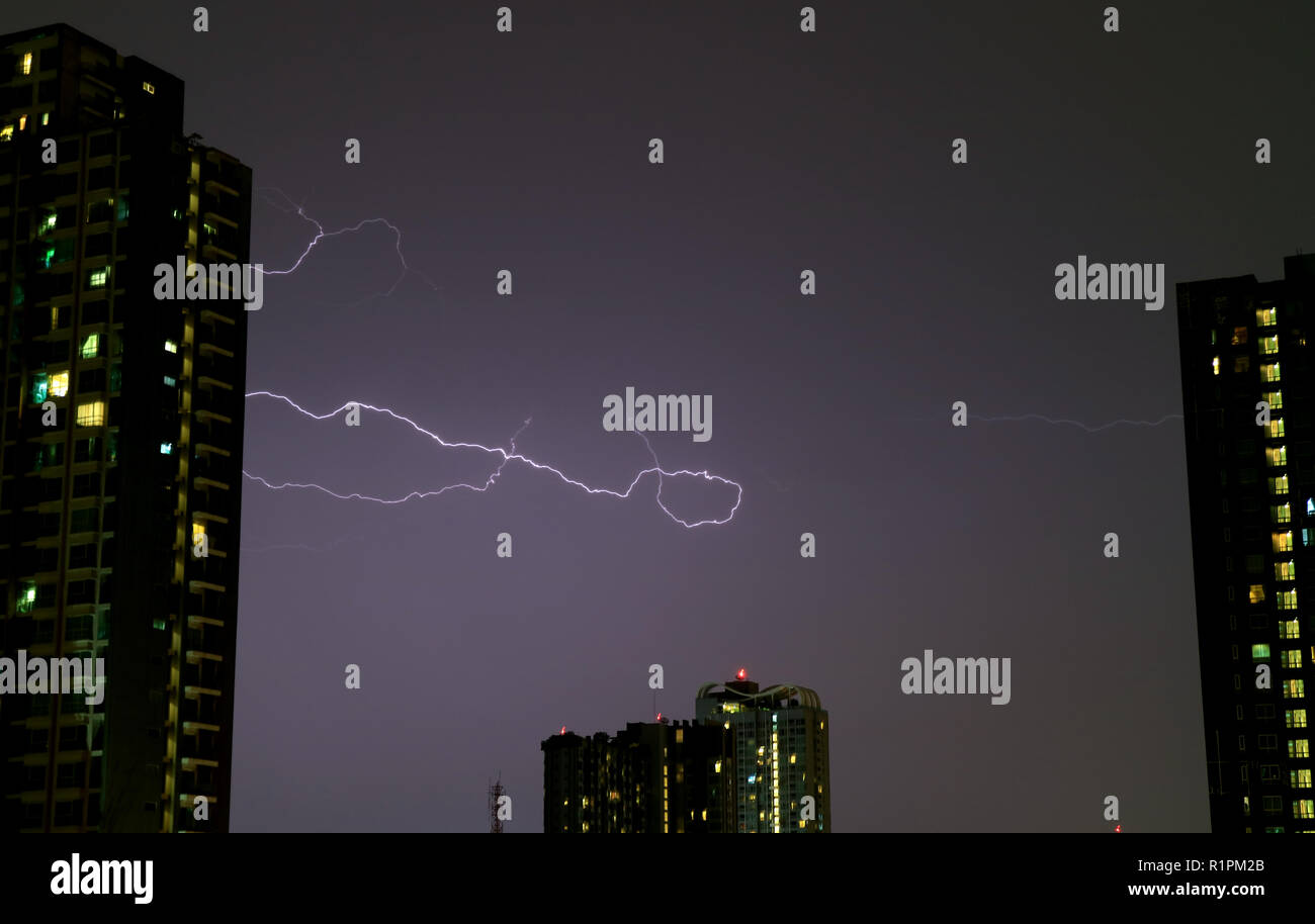 The Real Lightning Flashing on Night Sky over the High Buildings Stock Photo