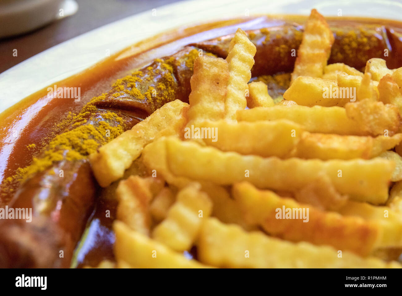Currywurst (curry wurst, German Sausage) and French Fries close up food photography. Germany dish, German food, paprika, spicy. Stock Photo